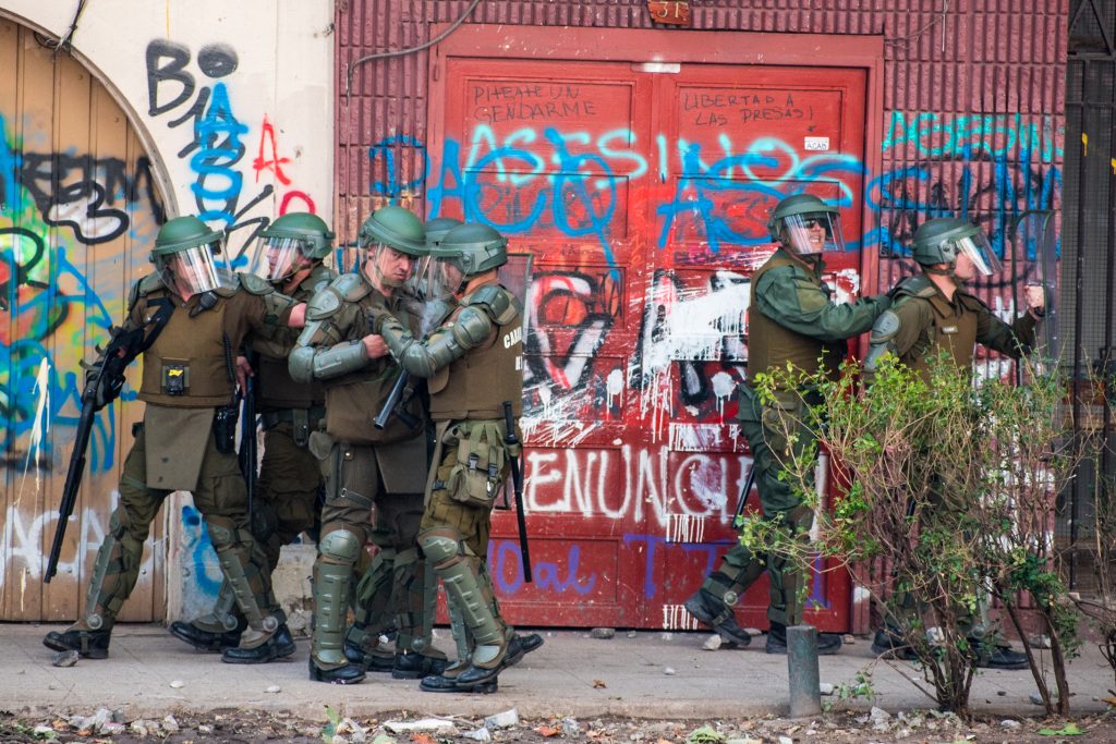 Des policiers chiliens devant des graffitis