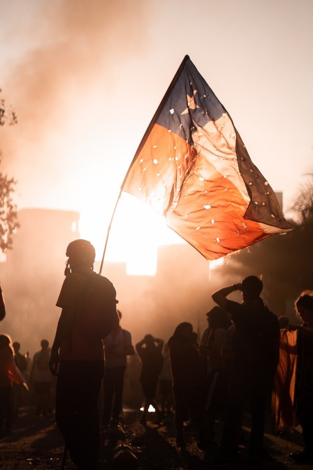 homme brandissant un drapeau dans un manifestation de nuit