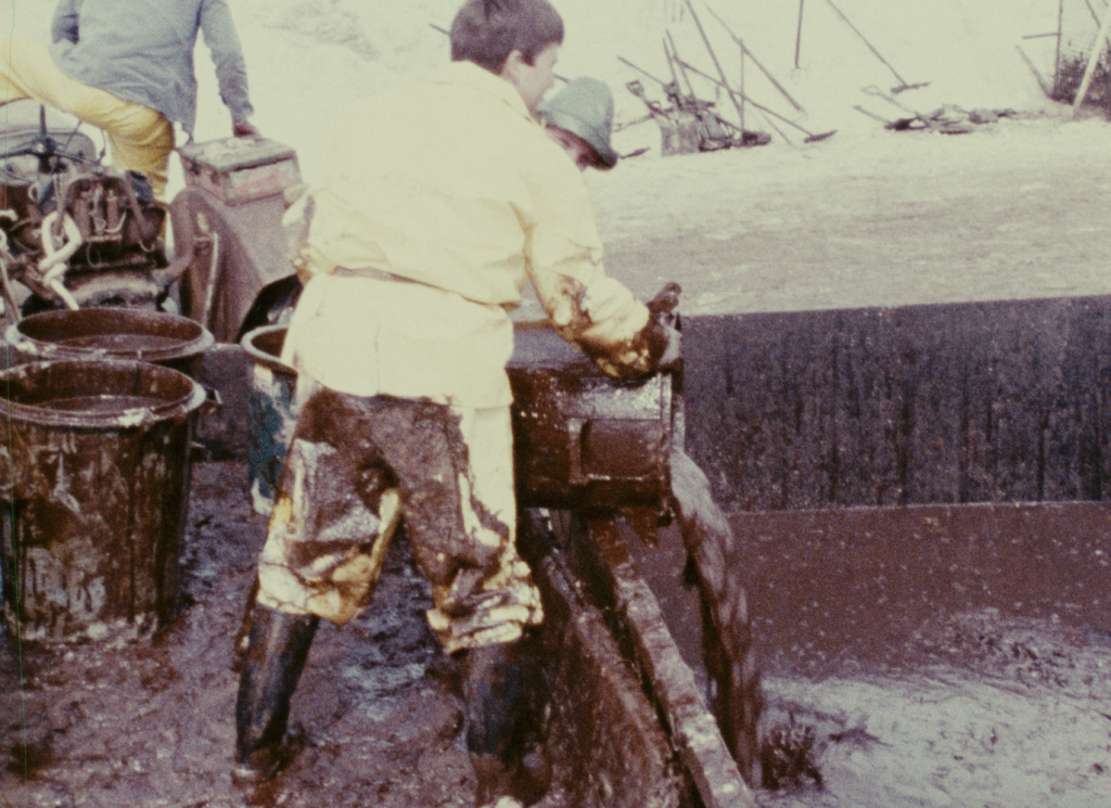 Un marin verse un seau de pétrole dans une cuve. 
