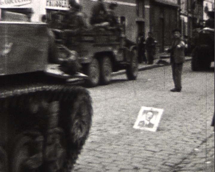 Chars circulant dans une rue, avec un portrait d'Hitler au sol