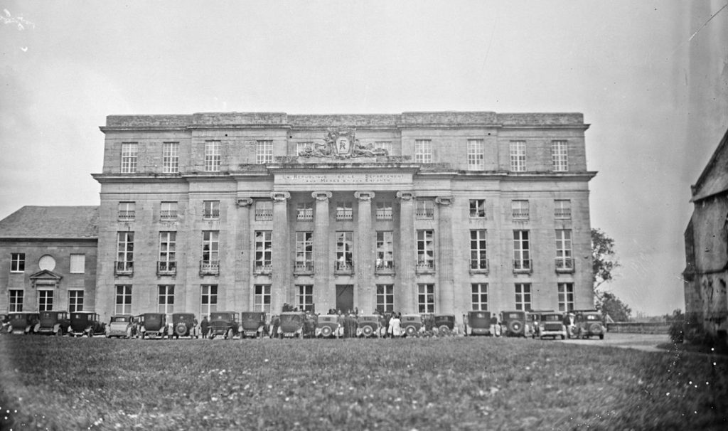 Photographie en noir et blanc du château de Bénouville, une grande bâtisse en pierres avec hautes fenêtres et colonnades
