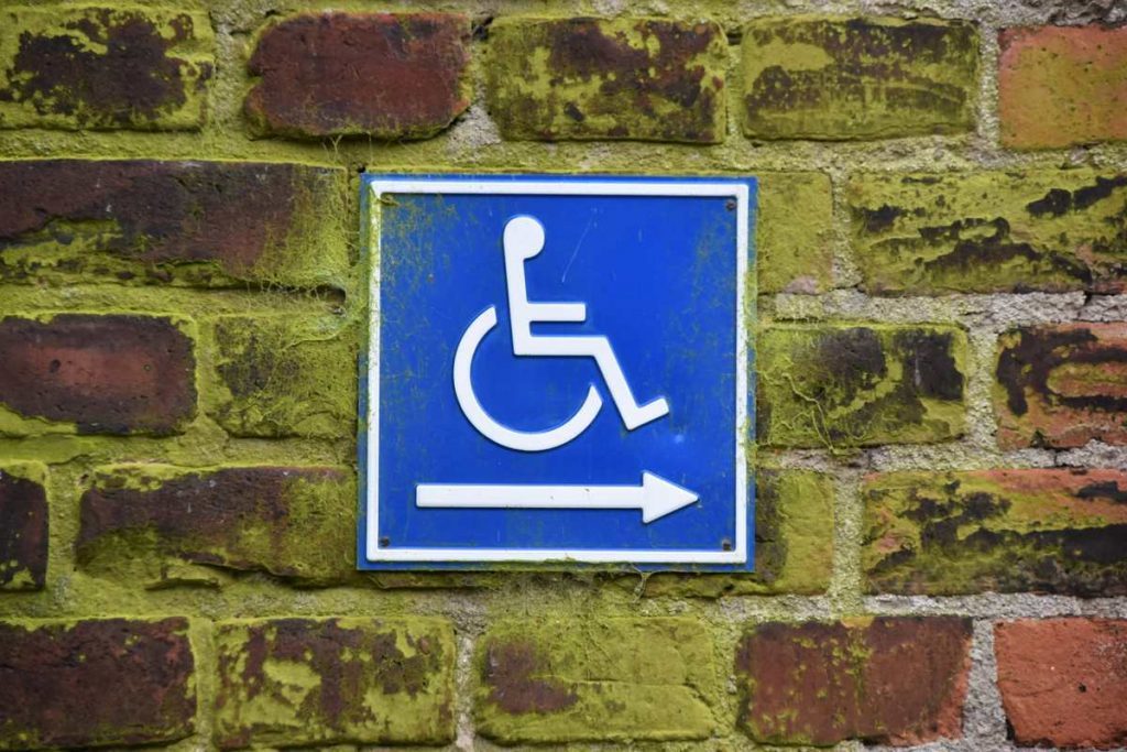 Une pancarte signalant un accès handicapé sur un vieux mur