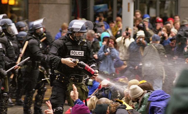 Des policier projet du gaz sur des manifestants assis