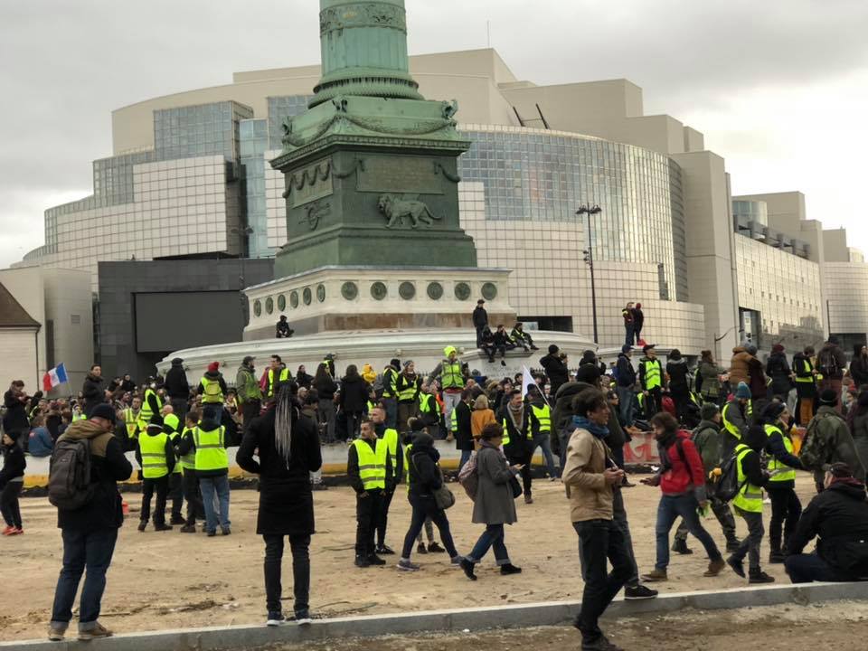 Plusieurs dizaines de personnes réunies sur la Place de la Bastille,  certaines portant des Gilets Jaunes