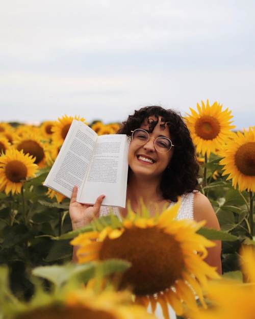 Portrait photographique d'Audrey dans un champ de tournesol, un livre ouvert à la main