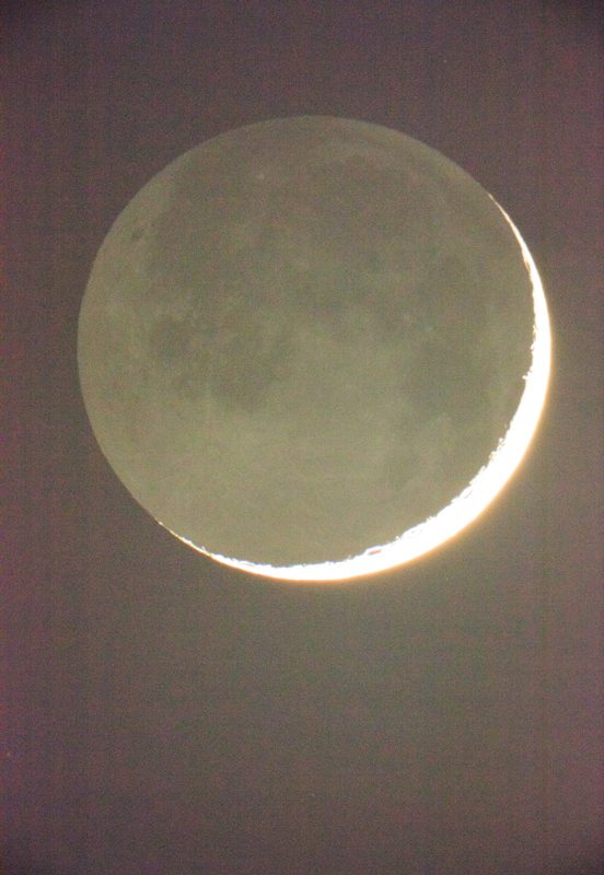 Moon in Earthlight de Wolfgang Tillmans, réalisée en 2015, capture un moment céleste fascinant : un croissant de Lune finement éclairé par la lumière directe du Soleil, tandis que le reste du disque lunaire est subtilement visible grâce à la lumière réfléchie de la Terre, appelée lumière cendrée. Le contraste saisissant entre la bande brillante, presque incandescente, du croissant et les détails plus diffus du reste de la Lune crée une ambiance mystérieuse et poétique. Les nuances douces de gris, de vert et de jaune traversent la surface lunaire, faisant ressortir ses reliefs et ses mers sombres. L’arrière-plan est plongé dans une obscurité profonde, renforçant l’impression d’apesanteur et d’immensité cosmique. Par cette œuvre, Tillmans unit une approche scientifique rigoureuse de l'observation astronomique à une sensibilité artistique rare, traduisant l’émotion brute de contempler notre satellite naturel."