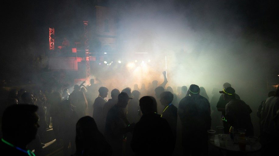 Des silouhettes dansent sur une piste de danse, au milieu d'un nuage de fumée.