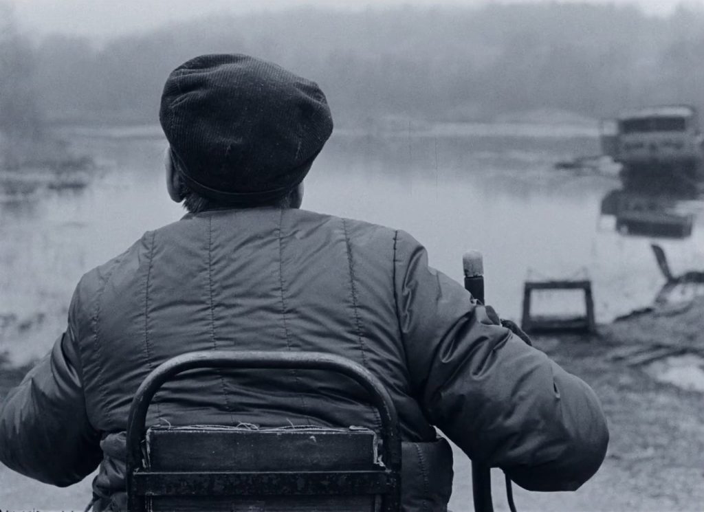 Un homme à la casquette de dos regarde un lac