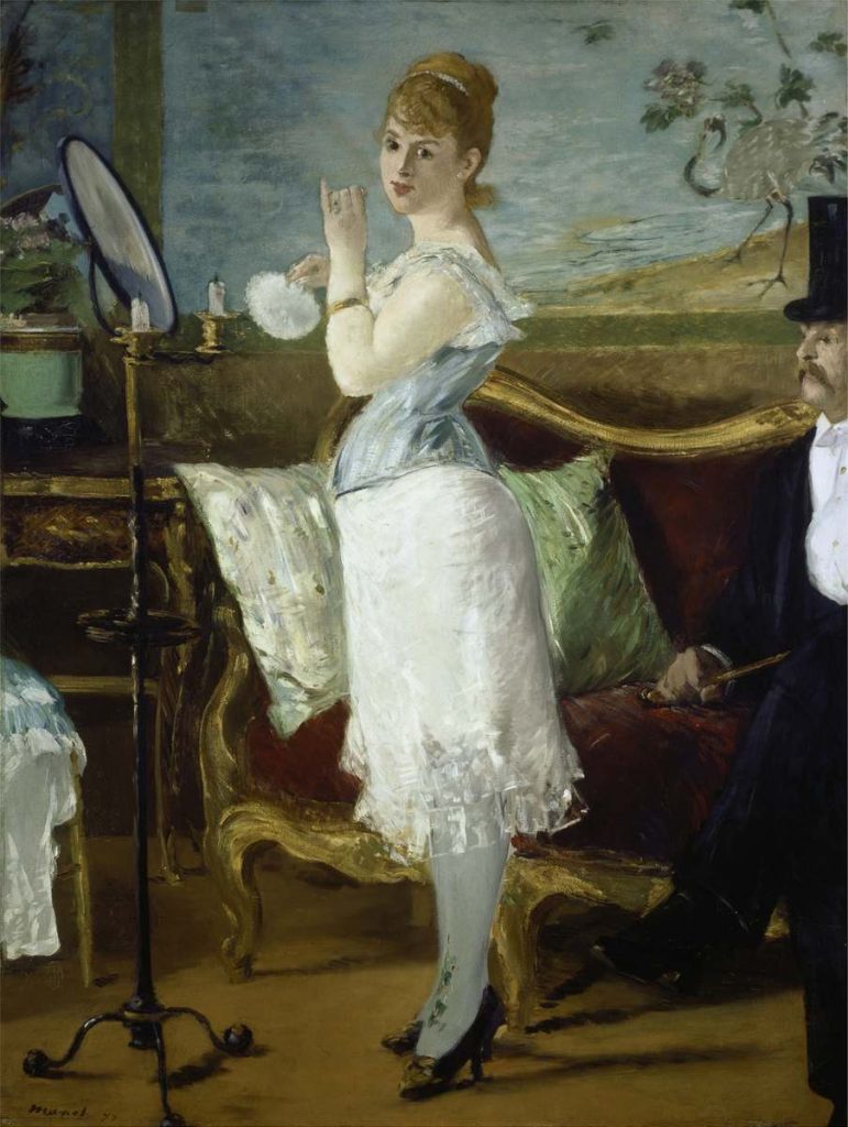 Jeune femme, en pied, de maquillant devant le miroir. Elle est bustier et jupon et regarde en direction du peintre, une houpette à la main.