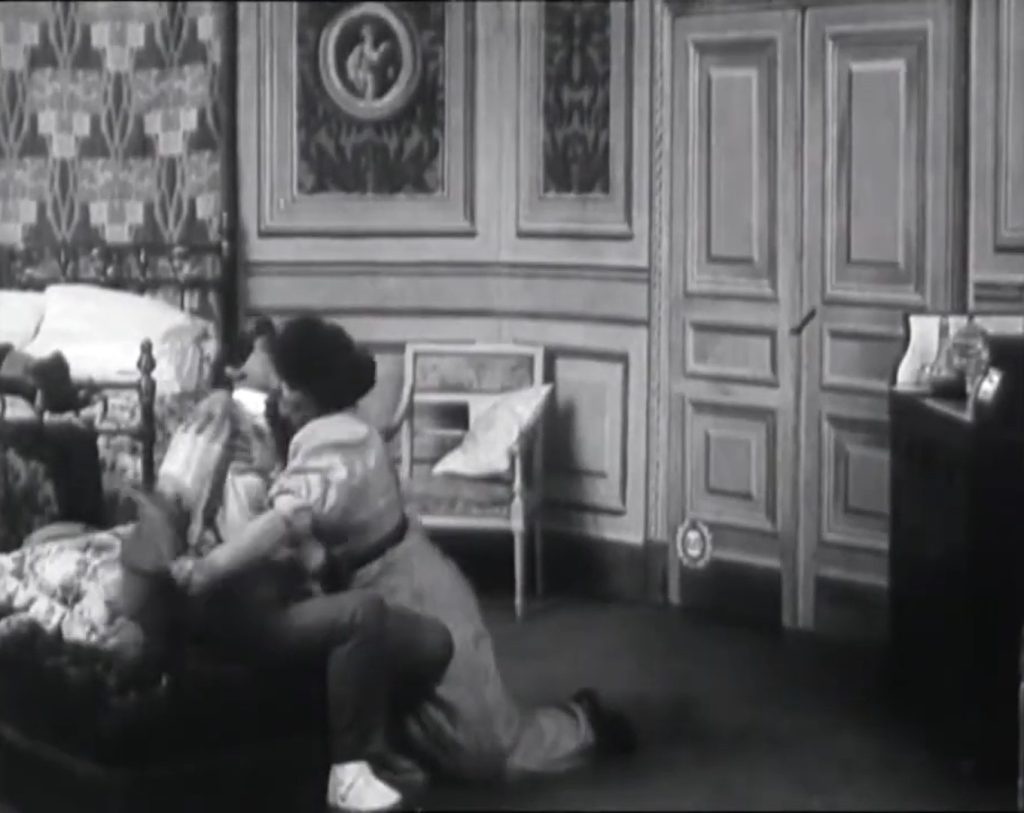 Une femme déshabille un homme près d'un lit