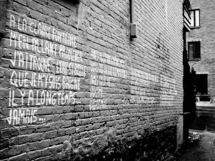 À la claire fontaine : comptine écrite sur un mur de brique (noir et blanc)