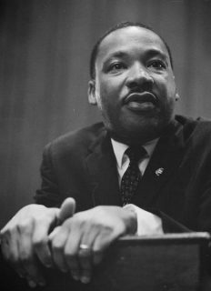 Martin Luther King, penché sur un pupitre, 1964