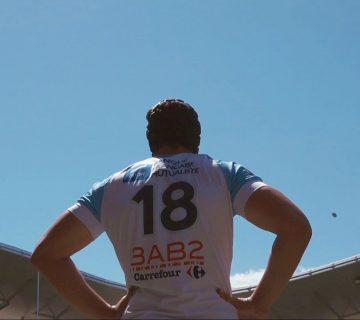 Un joueur de rugby de dos regarde le ballon qui arrive haut dans le ciel