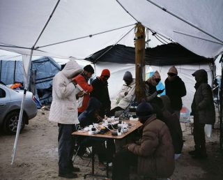 Des migrants rechargent leurs téléphones sous une tente.