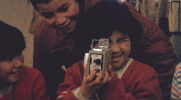 Un enfant regarde dans un caméra 8mm.
