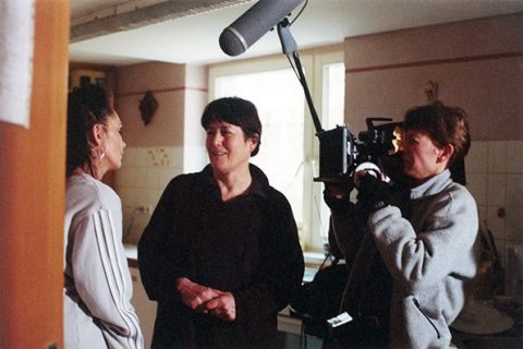Helga Reidemeister parle à un personnage, à côté d'une camerawoman et d'un preneur de son.