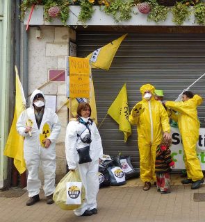 personnes manifestant en tenue de sécurité avec logo nucléaire et masques