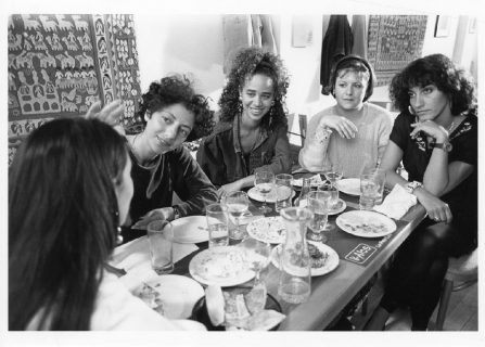 Photo en noir et blanc d'un groupe d'amies discutant autour d'un repas.