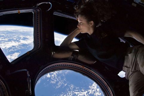 Jeune femme admirant la Terre par un hublot depuis l'espace