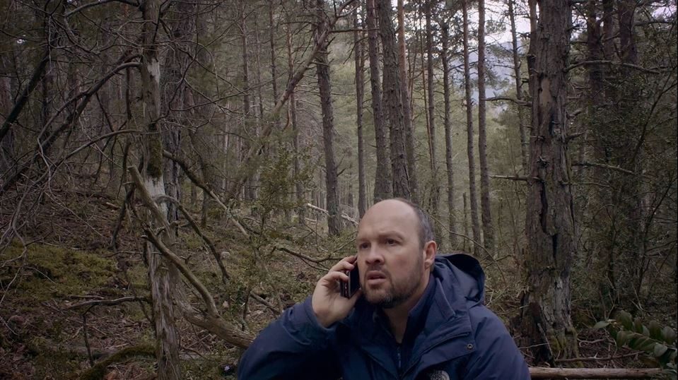 Un homme téléphone au milieu d'une forêt.