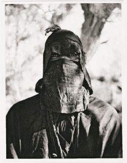 Photo en noir et blanc d'un homme portant un foulard sur le haut et le bas du visage, ne laissant voir que ses yeux.