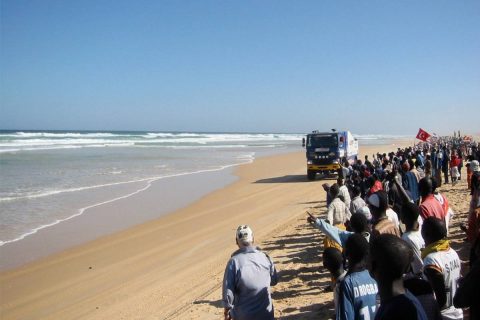 Spectateurs assistant au passage d'un camion du rallye sur la plage