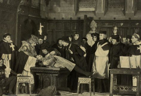 Photographie en noir et blanc de comédiens costumés en ecclésiastiques, penchés sur le corps d'une comédienne incarnant Jeanne d'Arc