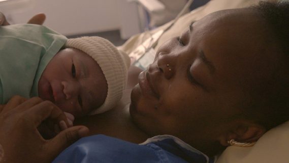 Une femme, allongée sur un lit d'hôpital, tient son nouveau né dans ses bras