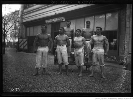 Six hommes gymnastes, torses nus, placés côte-à-côte