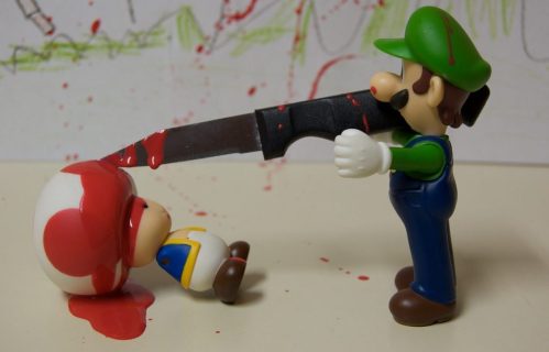 Mise en scène d'une figurine de Luigi, tenant un couteau planté dans la figurine d'un autre personnage (Toad). Du ketchup fait office de sang