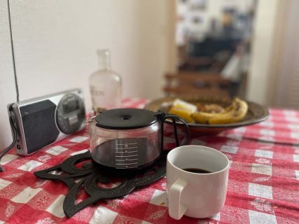 Sur la table d'une cuisine, des objets du quotidien (tasse à café, radio, cafetière...)