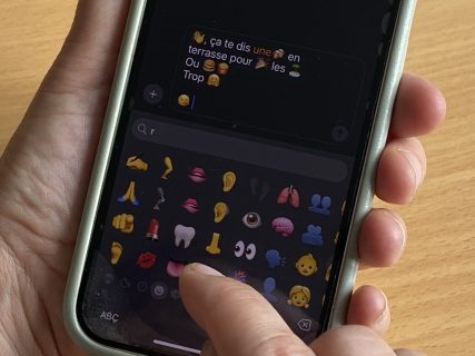 Gros plan sur un smatrphone. Une personne est en train de saisir un message avec plein d'émojis.