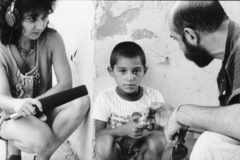 Un homme et une femme, tenant un micro et accroupis, interrogent un petit garçon