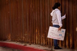 Jeune fille devant le mur de séparation Etats-Unis / Mexique